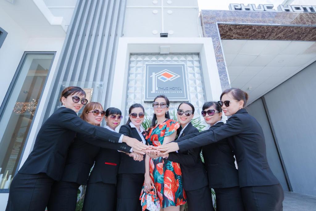 a group of people holding hands in front of a building at Phuc Hotel in Cao Lãnh