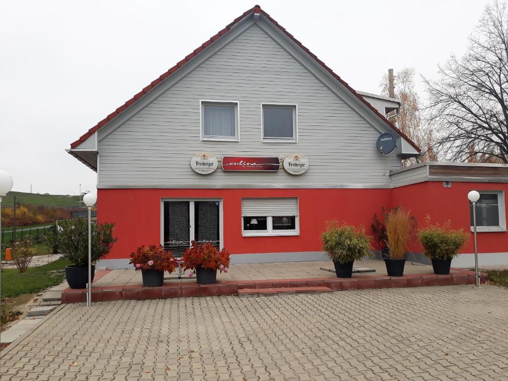 ein rotes und graues Gebäude mit Pflanzen davor in der Unterkunft Culina in Oberlungwitz