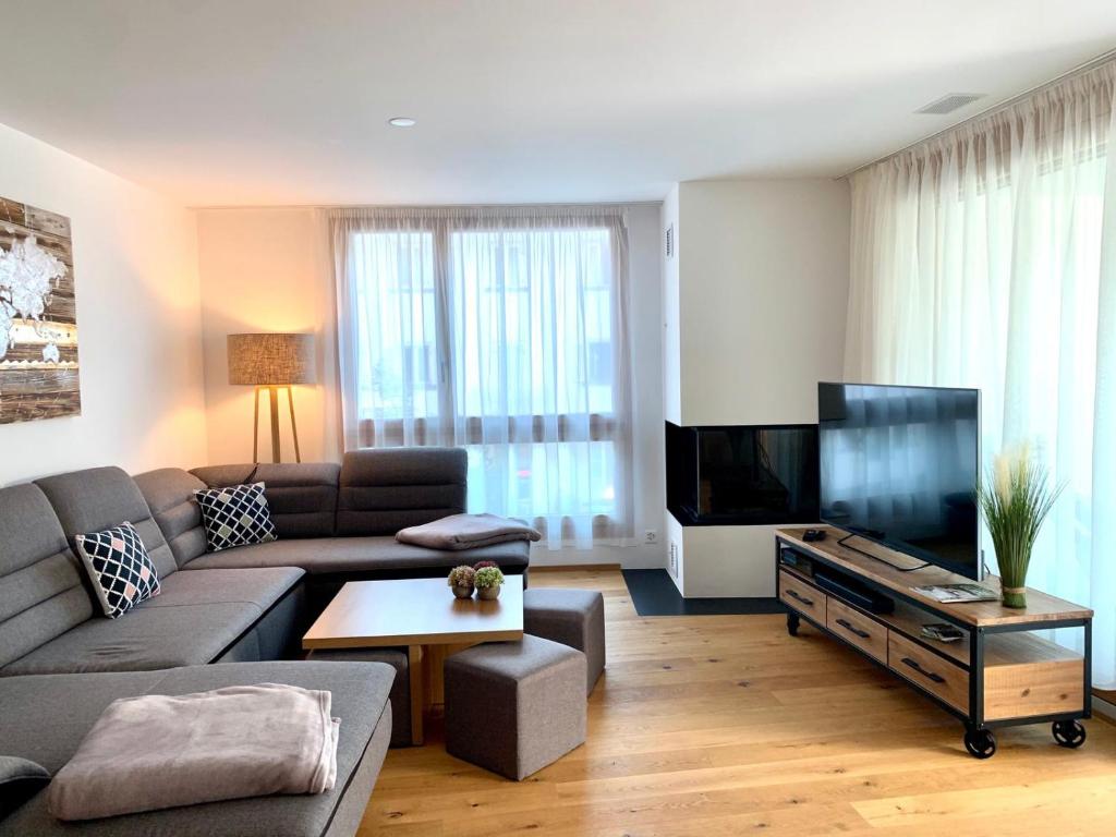un soggiorno con divano e TV a schermo piatto di Luxus Neubau 5 min zu Talstation & Caumasee a Flims