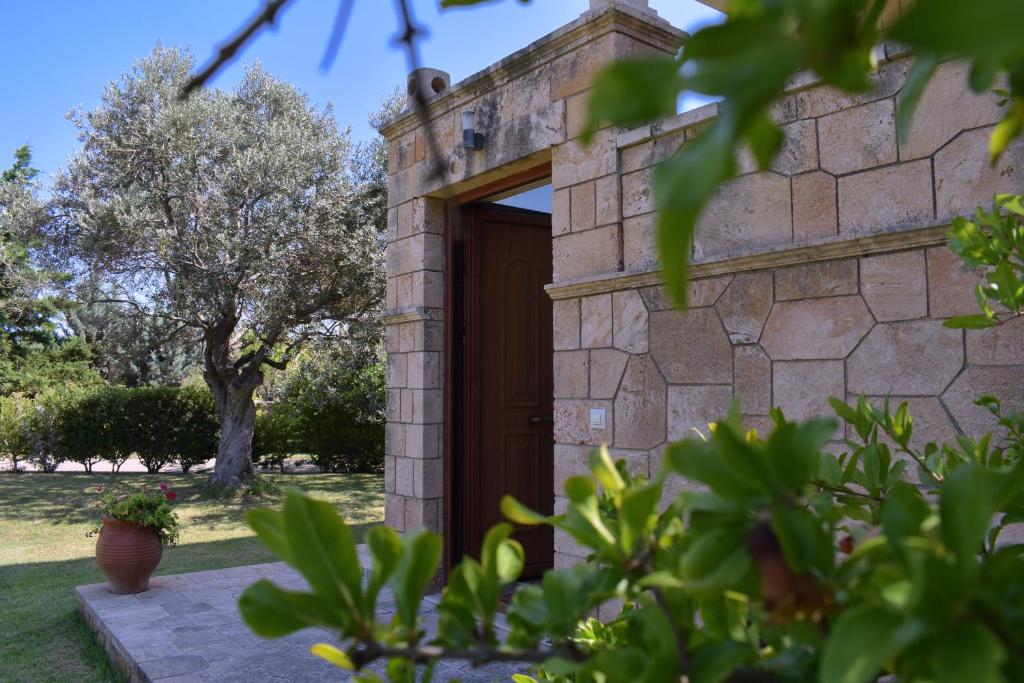 uma casa de pedra com uma porta de madeira num quintal em Seaside "Stone & Light Villa" close to Aegina City em Khlóï