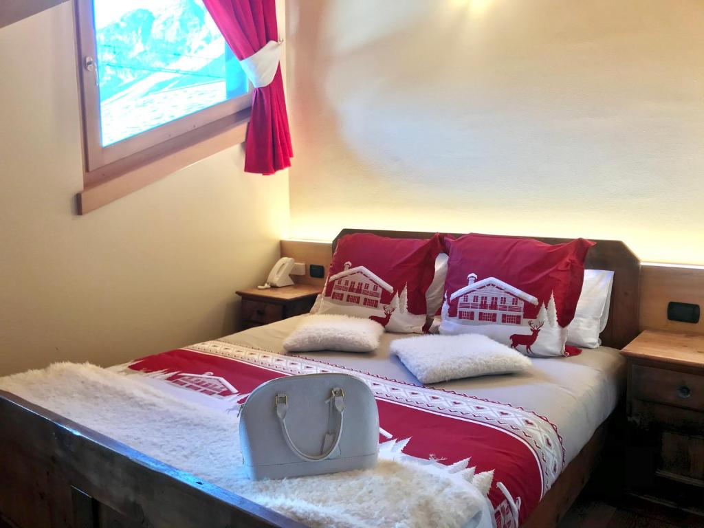 1 dormitorio con 1 cama con almohadas rojas y blancas en Chalet Bormino 5, en Bormio