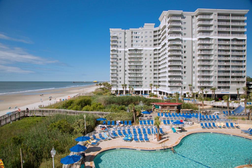 ein großes Hotel mit Pool, Stühlen und Strand in der Unterkunft Sea Watch Resort in Myrtle Beach