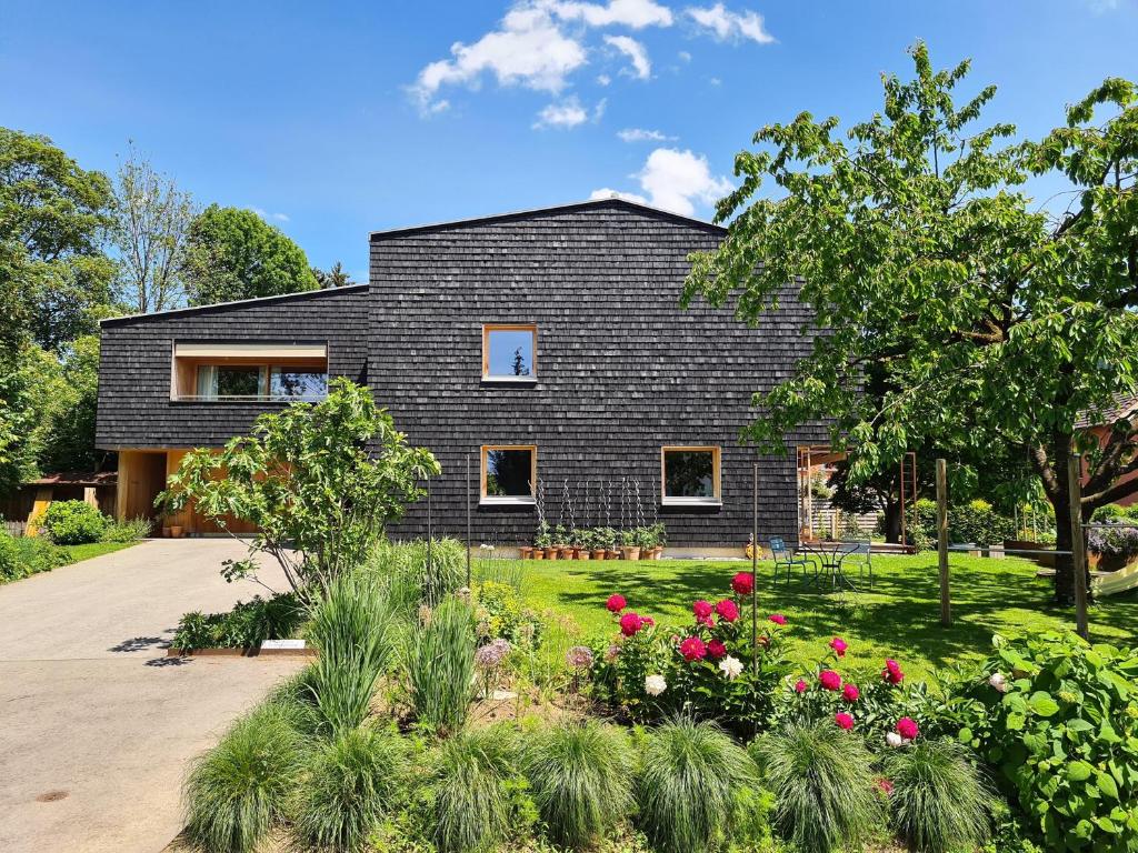 a black house with a garden in front of it at Bodensee-Ferienwohnung Am Ruggbach in Lochau