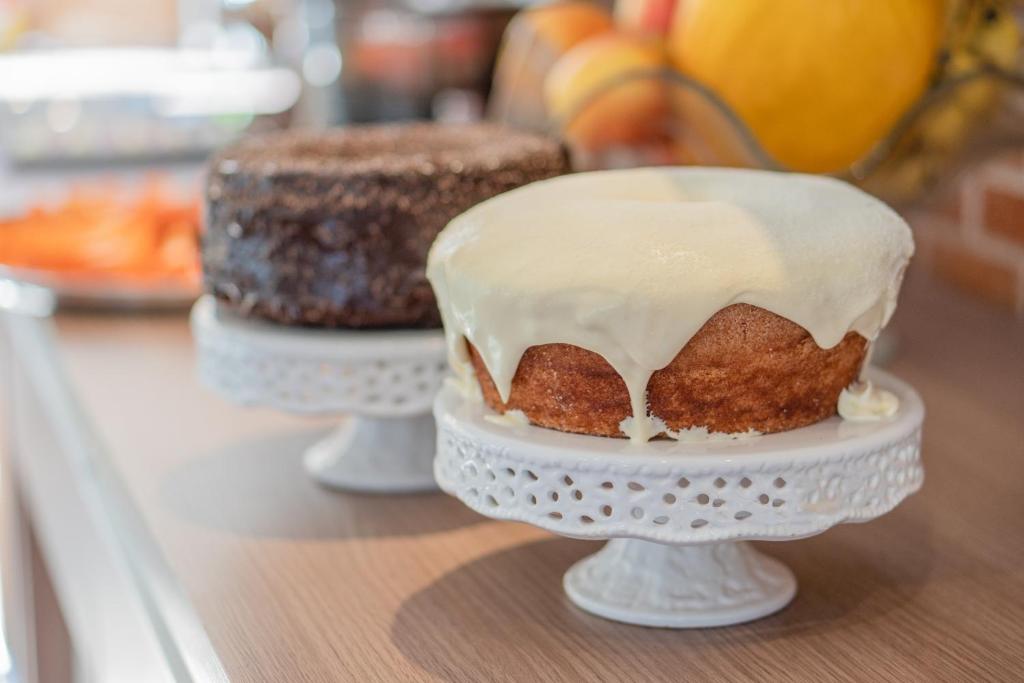 two cakes on plates on a counter with white frosting at Hotel Ipiranga Maringa in Maringá