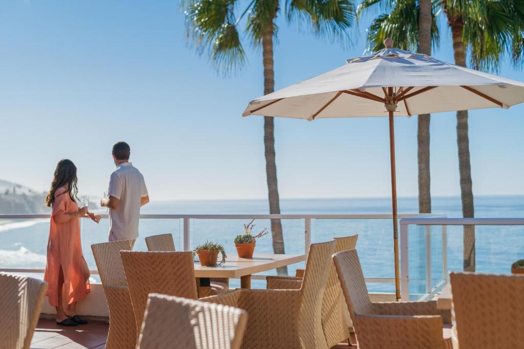 un hombre y una mujer de pie en un balcón con vistas al océano en Casa Loma Beach Hotel en Laguna Beach