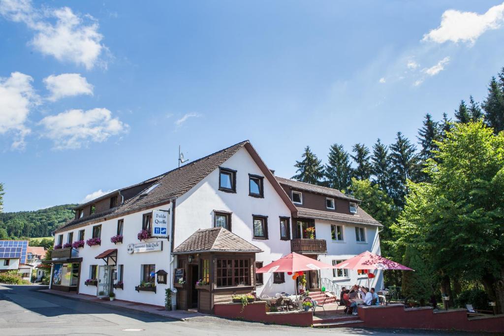 a white building with umbrellas in front of it at Genussgasthof Fuldaquelle & Berghof Wasserkuppe in Gersfeld