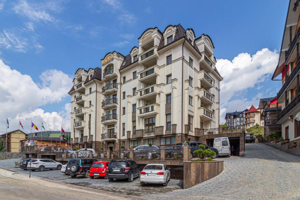 a large building with cars parked in front of it at MARION SPA Hotel & Spa - RENOVATION - Rooms, SPA area, Swimming pool, Reception, Restaurant, Lounge Bar, Hookah bar, Children's room, Parking, SPA and Breakfast included in the price in Bukovel