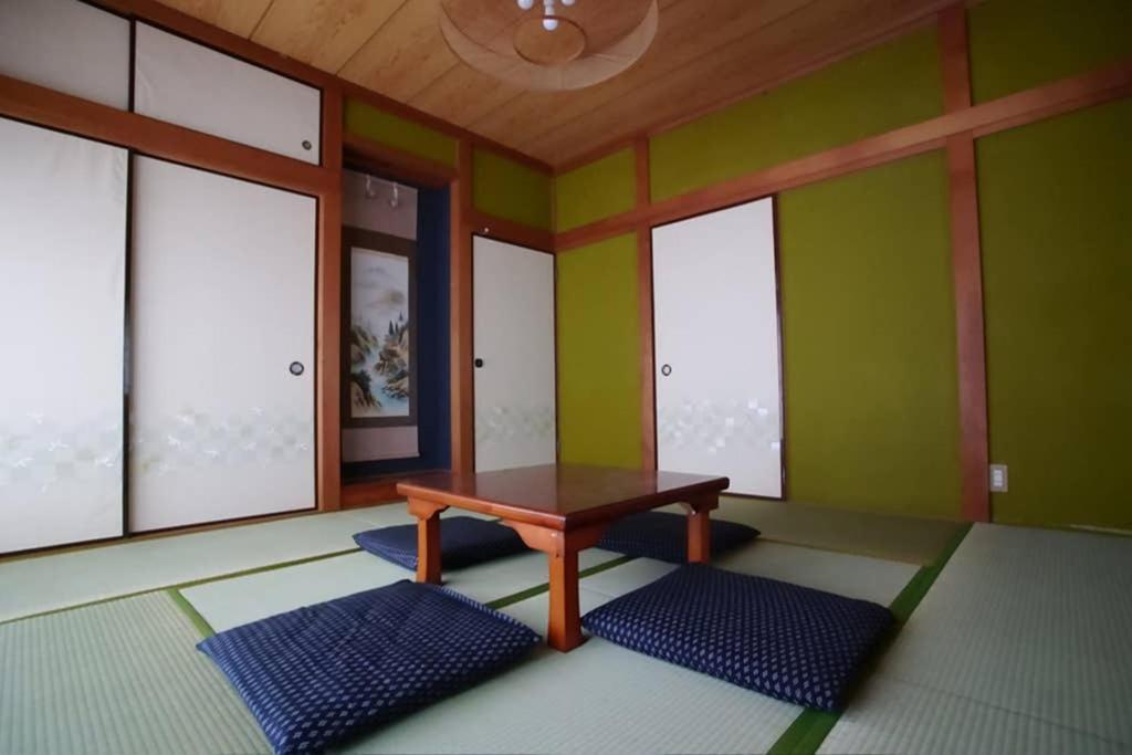 una camera con tavolo e alcune finestre di ゲストハウス八街 a Yachimata