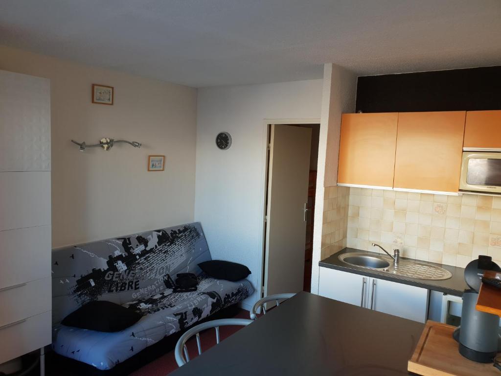 een woonkamer met een bank en een keuken bij studio 4/5 couchages puy saint vincent 1600 in Puy-Saint-Vincent