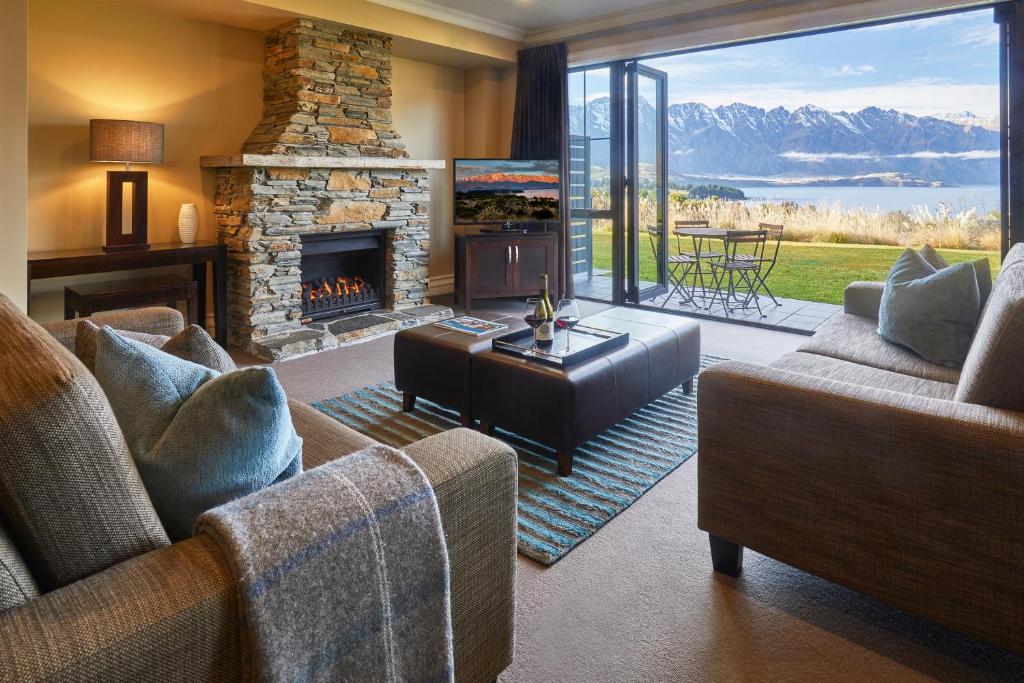 a living room with two couches and a fireplace at Platinum Queenstown in Queenstown