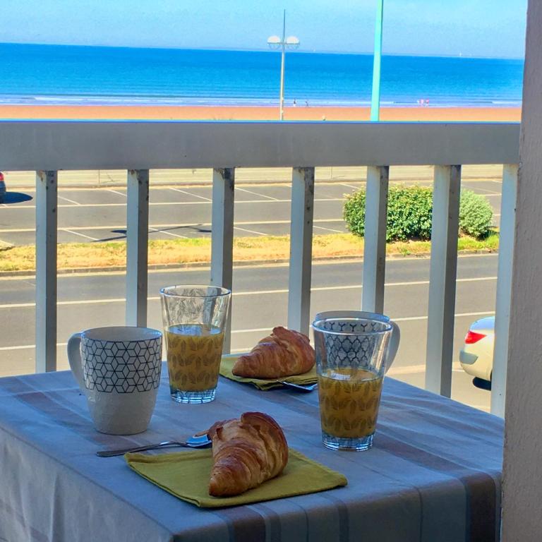 une table avec des croissants et des verres sur un balcon dans l'établissement L'esplanade, à Saint-Jean-de-Monts