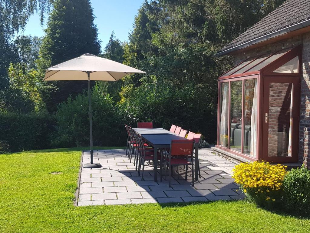 eine Terrasse mit einem Sonnenschirm, einem Tisch und Stühlen in der Unterkunft Nice holiday home in Sourbrodt near ski resort in Sourbrodt