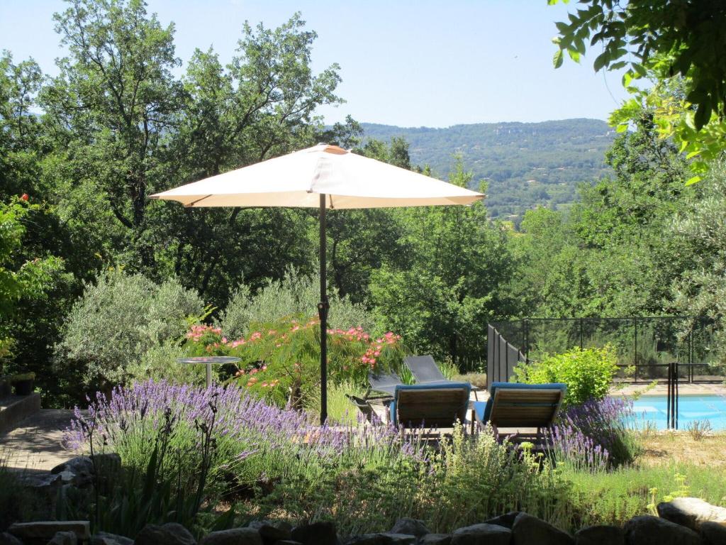 an umbrella and two chairs under it in a garden at Serena Villa in Saignon with Private Swimming Pool in Saignon