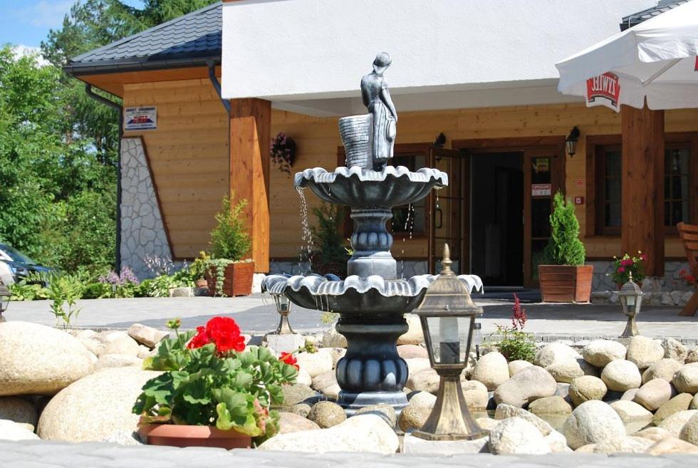a fountain in front of a building with a statue at Karczma na Woli in Biłgoraj