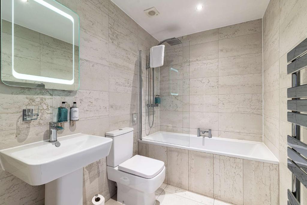 a bathroom with a sink and a toilet and a tub at The Bold Hotel; BW Signature Collection in Southport