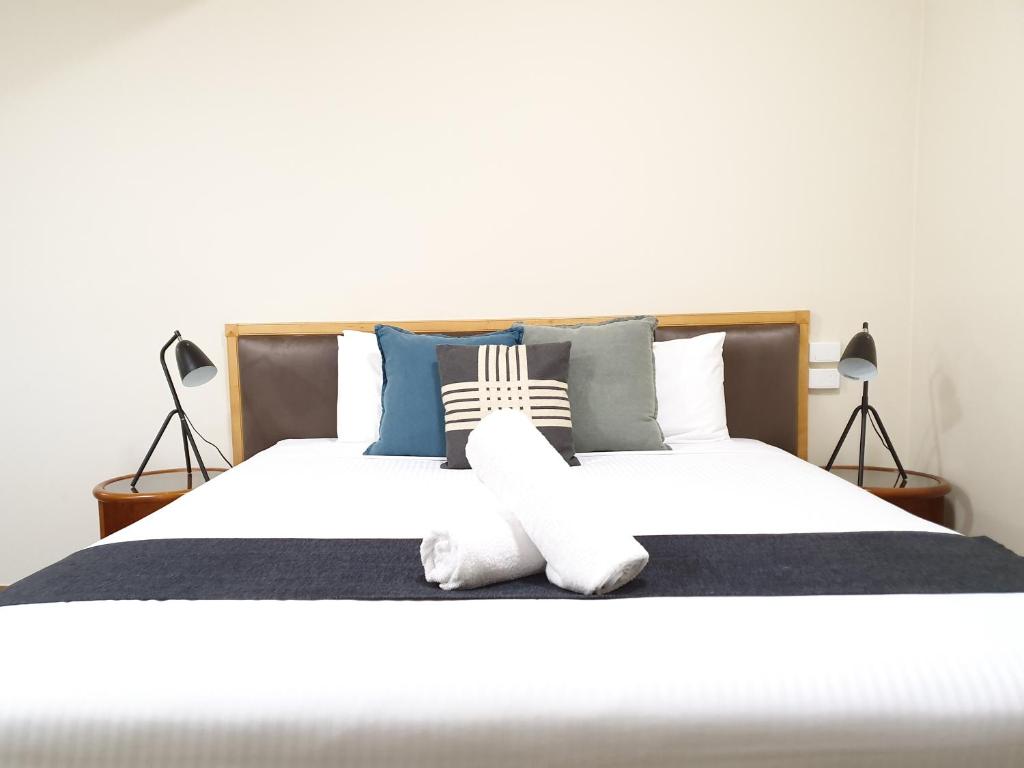 - une chambre avec un grand lit blanc et deux lampes dans l'établissement Bell Motel, à Melbourne