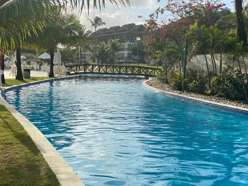 uma piscina com água azul e palmeiras em Beach class Muro Alto Flat em Porto de Galinhas