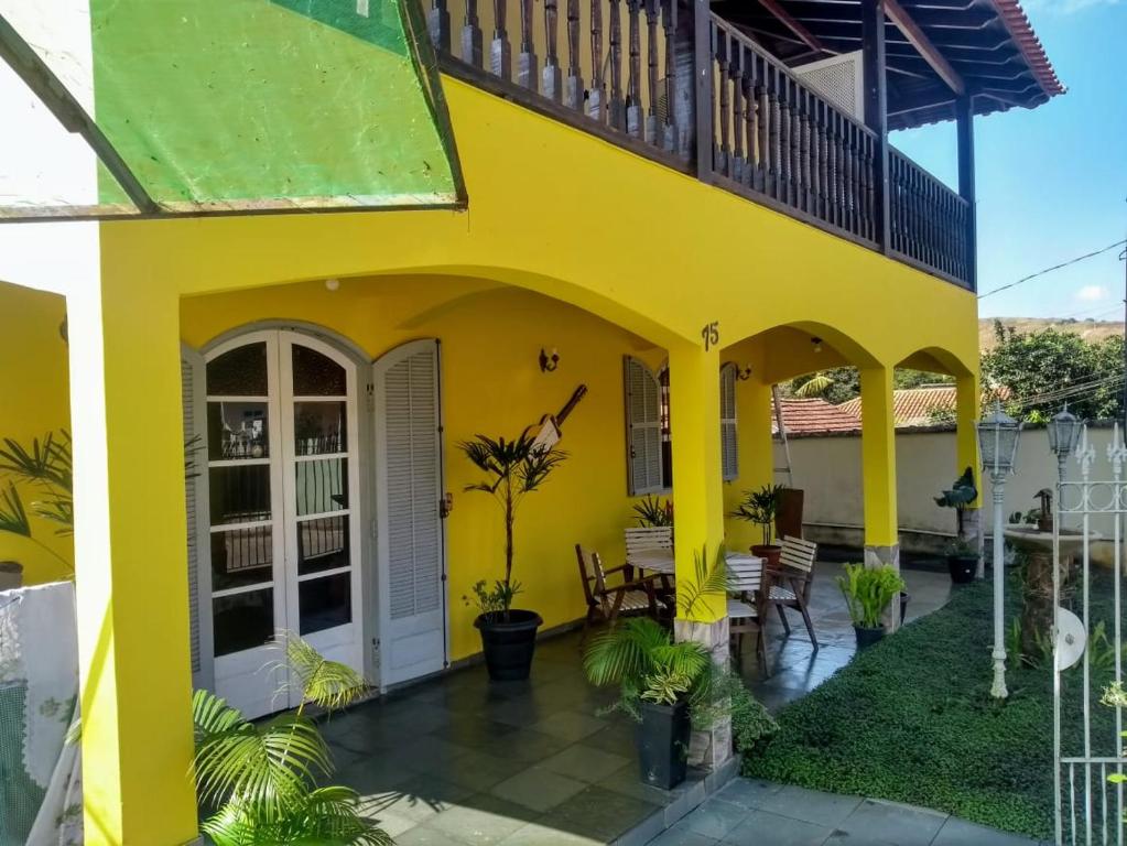 a yellow house with a balcony and a patio at Pousada Clave de Sol in Conservatória