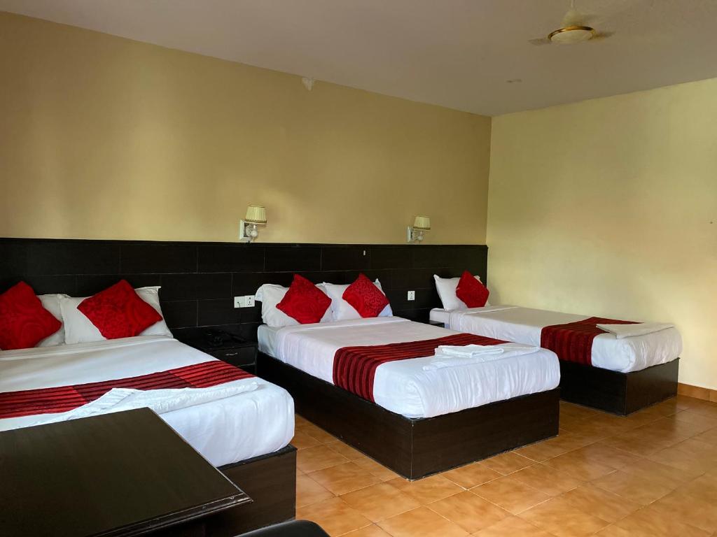 two beds in a hotel room with red pillows at Pokhara Cottage in Pokhara