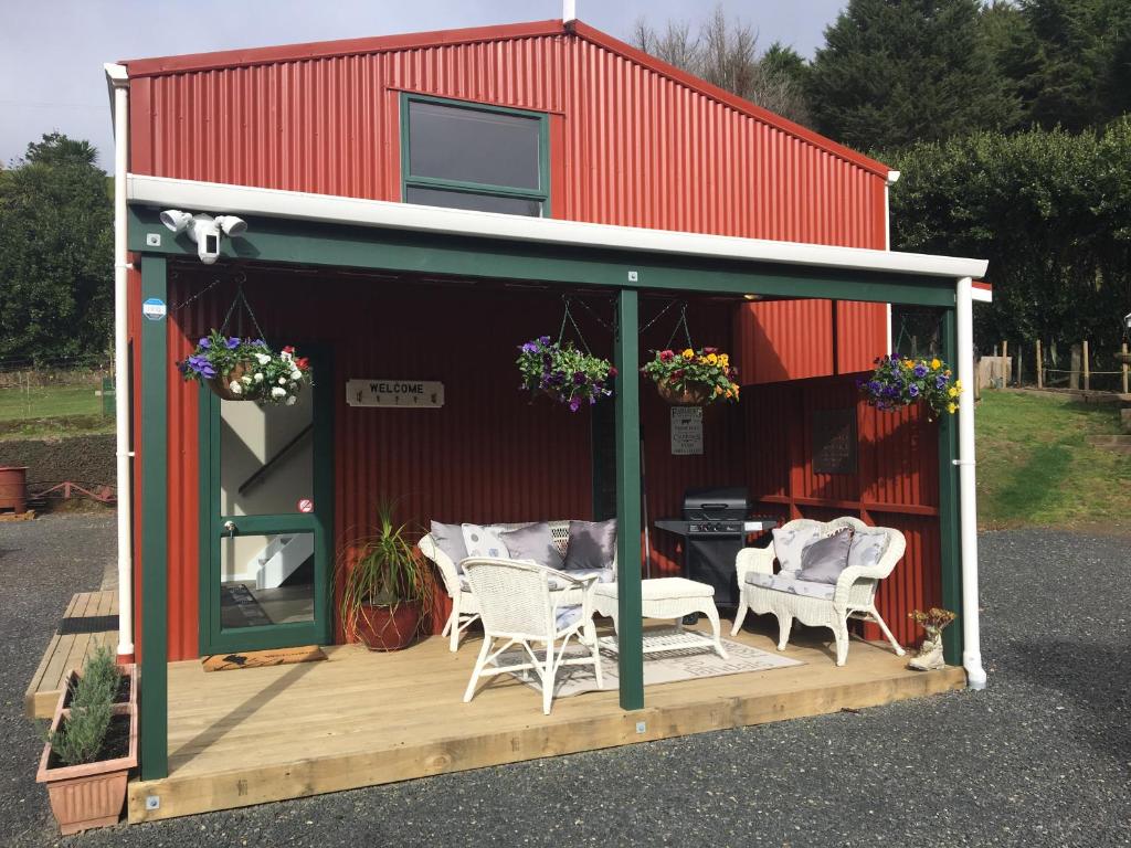 um barracão vermelho com cadeiras e uma mesa num deque em Beynon&Bolton’s Country Loft Escape em Katikati