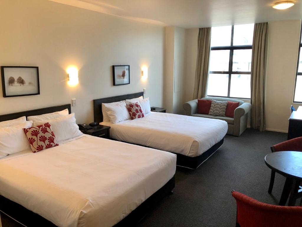 a hotel room with two beds and a chair at Distinction New Plymouth Hotel in New Plymouth