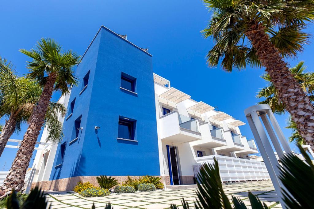 een blauw gebouw met palmbomen ervoor bij Sundeck Hotel in San Vito lo Capo