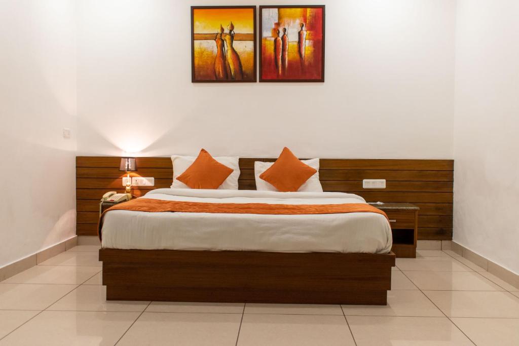 ein Schlafzimmer mit einem großen Bett mit orangefarbenen Kissen in der Unterkunft Grand Hotel Nawanshahr in Nawāshahr