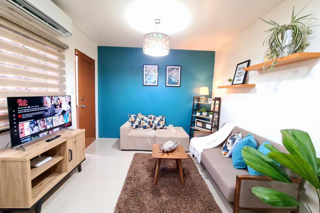 uma sala de estar com um sofá e uma televisão em Cozy Space Near SM with Netflix and Fiber WiFi em Batangas City