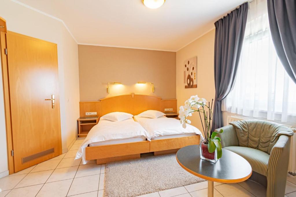 a hotel room with a bed and a chair and a table at Hotel Re'ser Stuff in Roeser