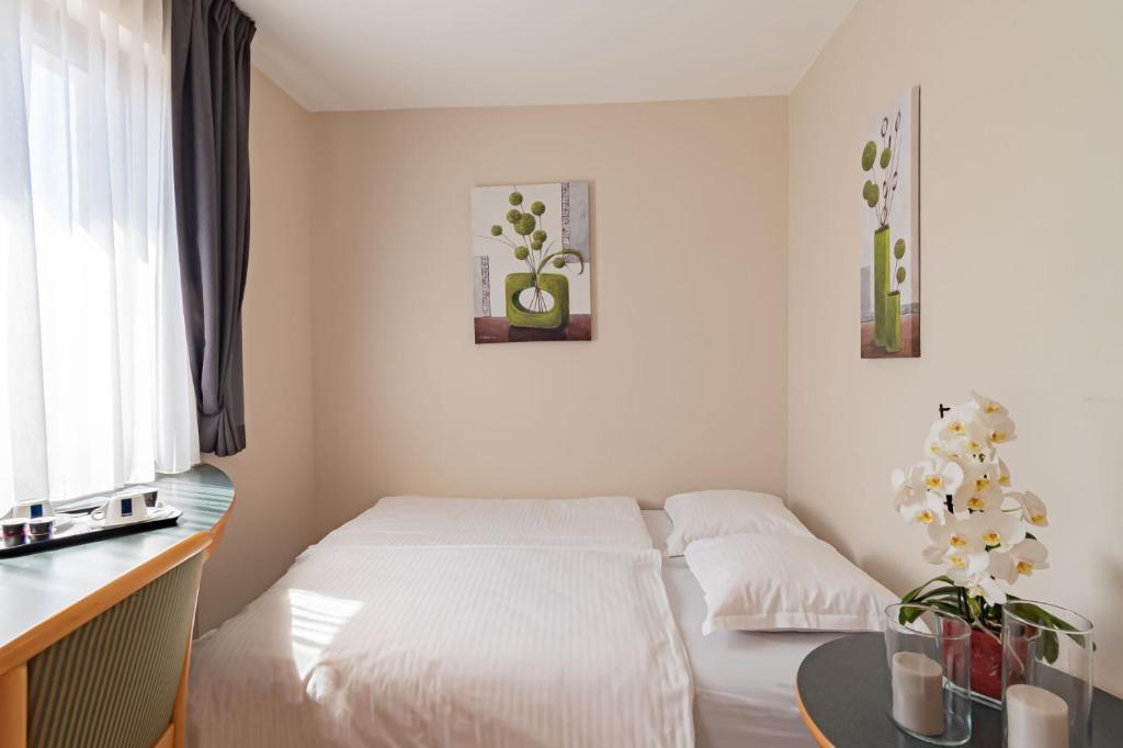 a bedroom with a white bed and a table at Hotel Re'ser Stuff in Roeser