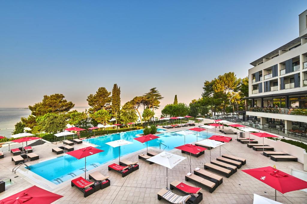 an overhead view of a pool with chairs and umbrellas at Hotel Parentium Plava Laguna in Poreč