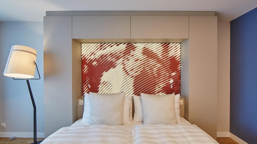 a bedroom with a bed with a red painting on the wall at Hotel Wettstein in Basel