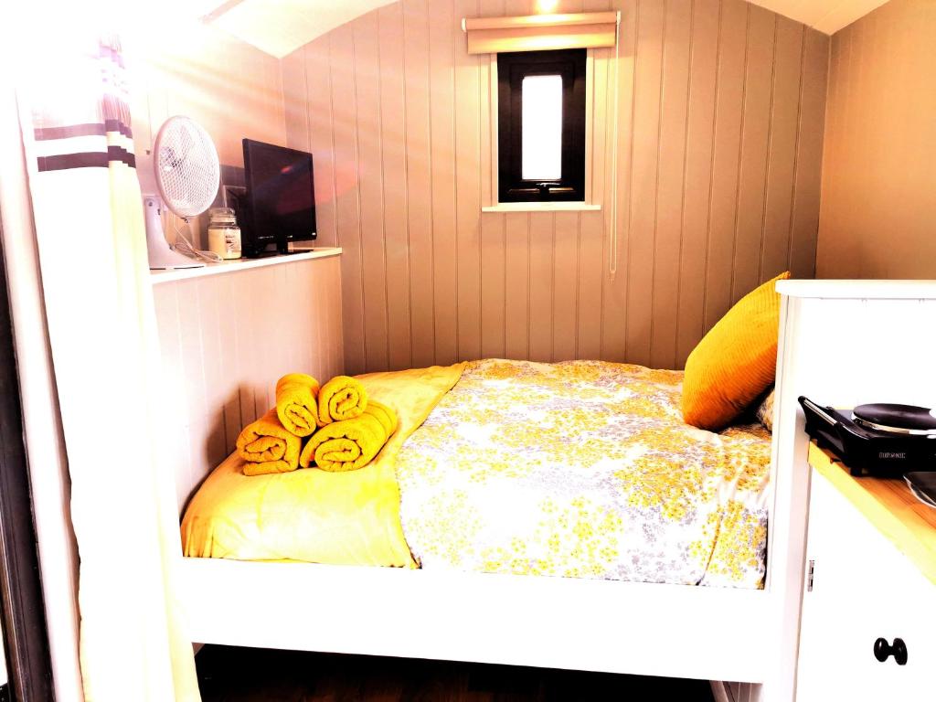 a room with a bed with yellow blankets on it at the cwch in Llanbister