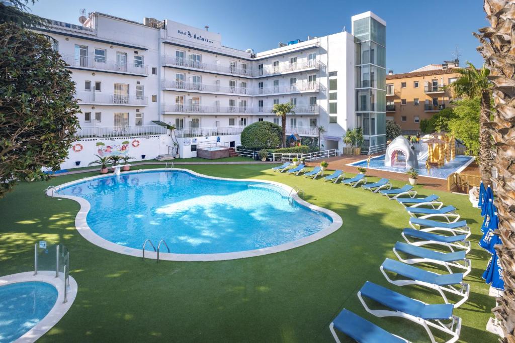 a large swimming pool with chairs in front of a building at GHT Balmes, Hotel-Aparthotel&SPLASH in Calella