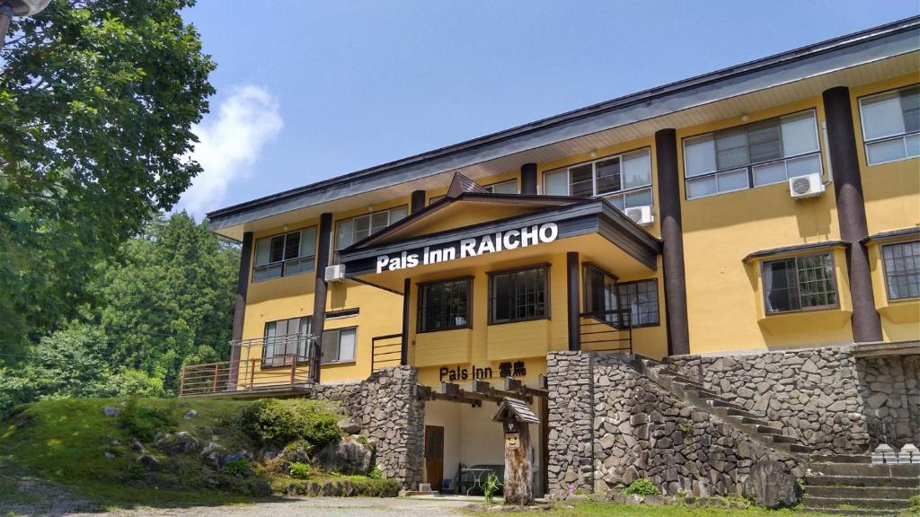 a yellow building with a sign that reads pas inn akko at Pals Inn Raicho in Hakuba
