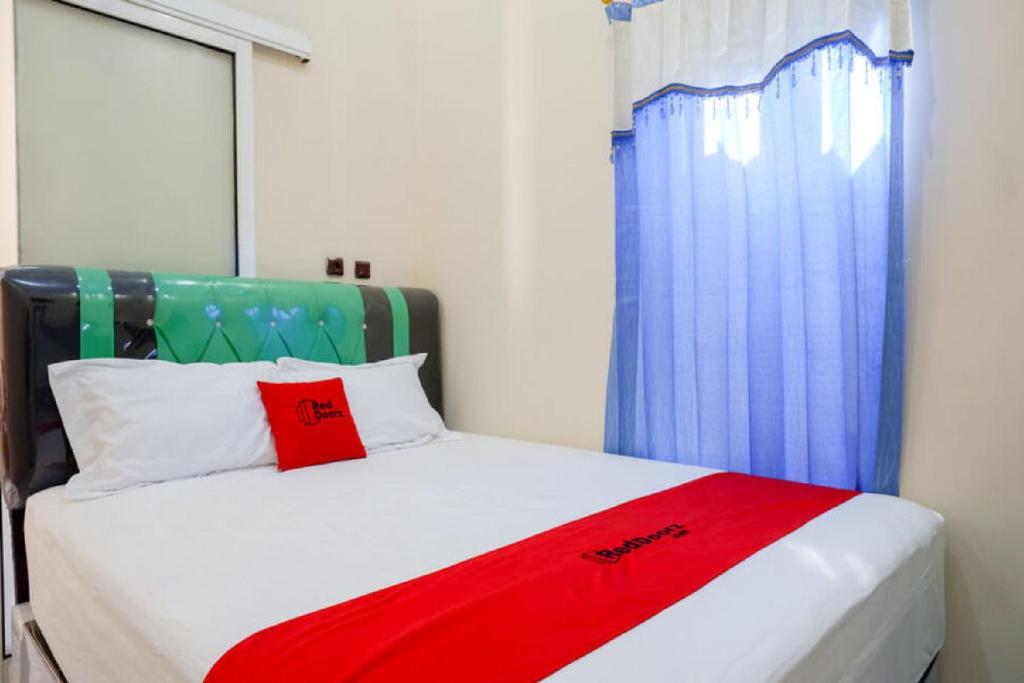 a bedroom with a bed with a red blanket on it at RedDoorz @ Jalan Raya Kaliwungu Selatan Kendal in Kendal