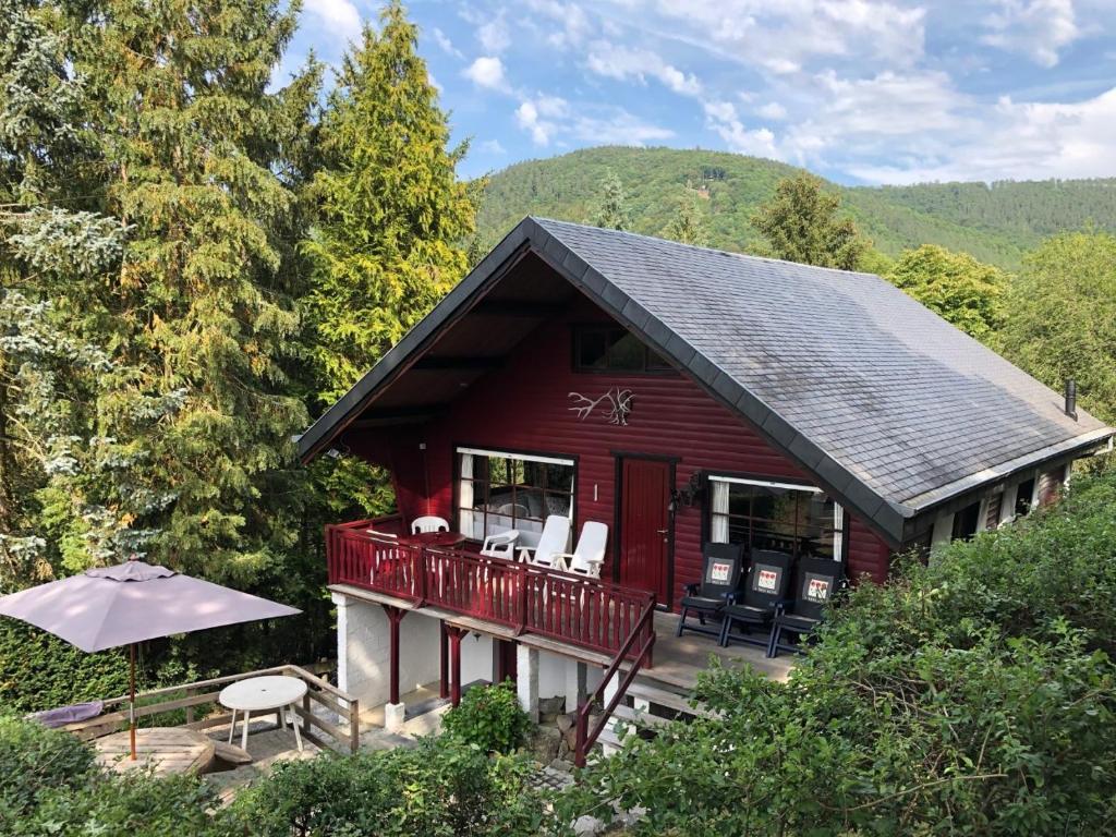 a red house with a deck with chairs and an umbrella at Chalet Grand Coo in Stavelot