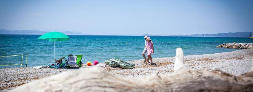 a man standing on a beach with an umbrella at La Madonnina Village Resort in Follonica