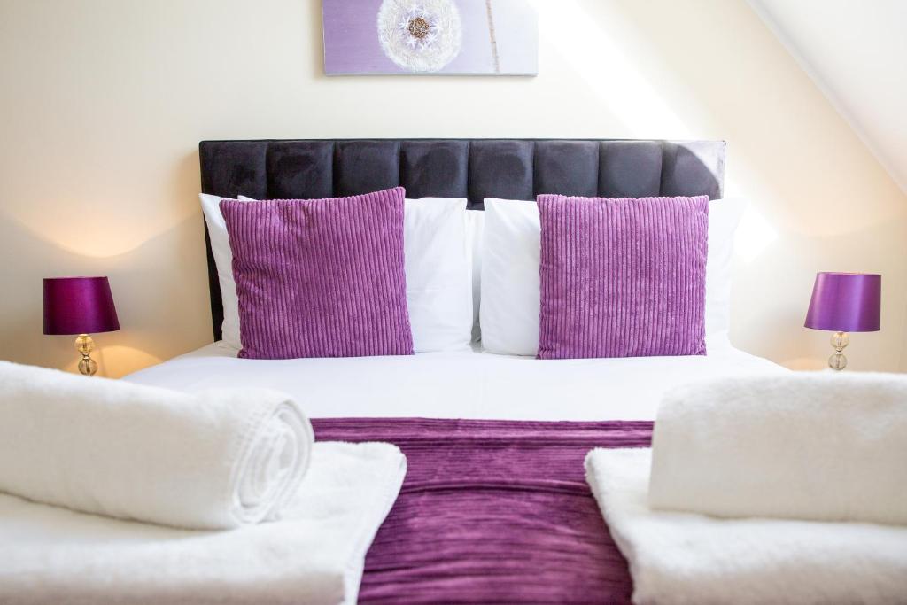 a bedroom with a large bed with purple and white pillows at Velvet 2-bedroom apartment, Clockhouse, Hoddesdon in Hoddesdon