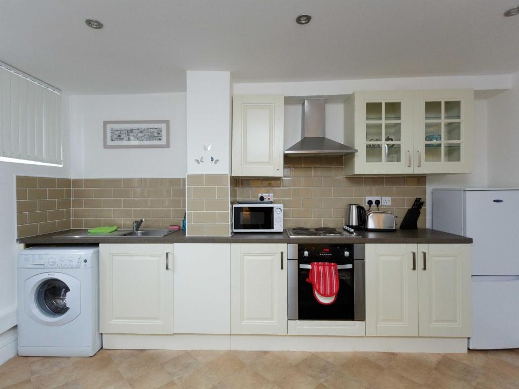 a kitchen with white cabinets and a stove top oven at Vine Studio in Leeds
