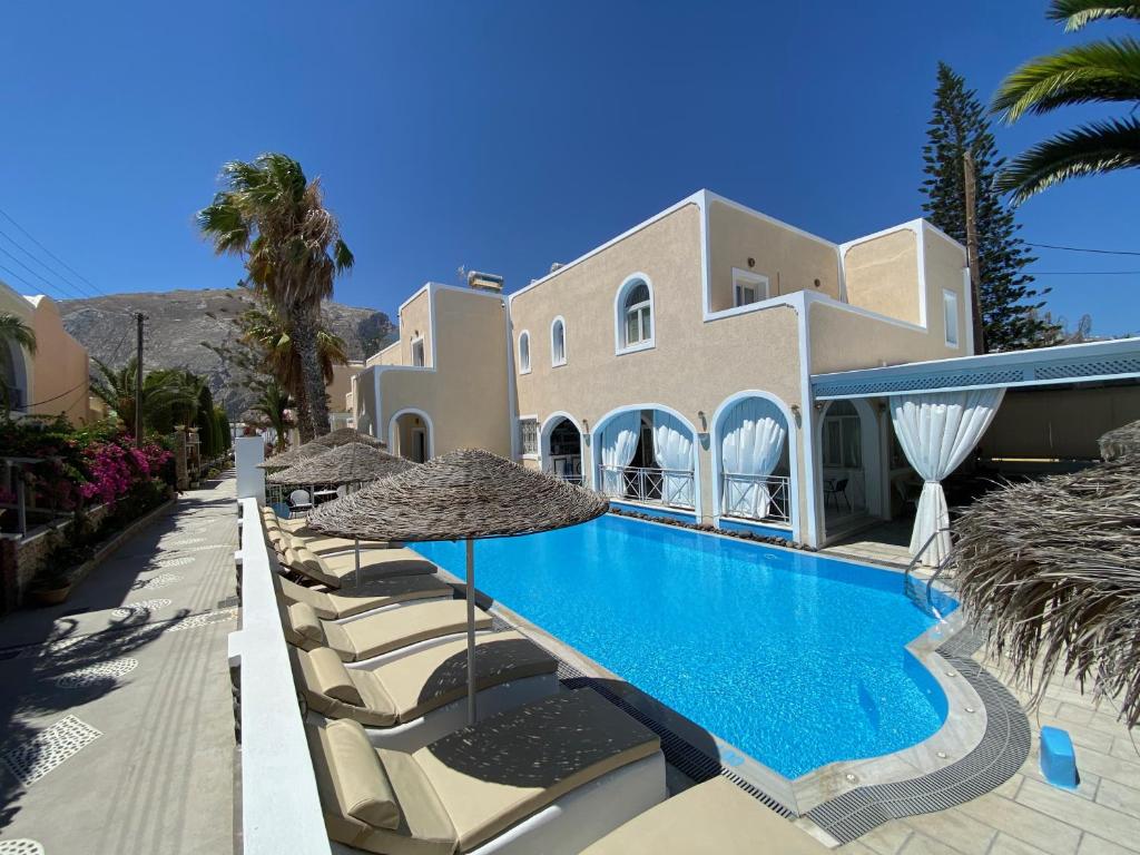 a villa with a swimming pool with chairs and umbrellas at Dioskouri Art Villas in Kamari