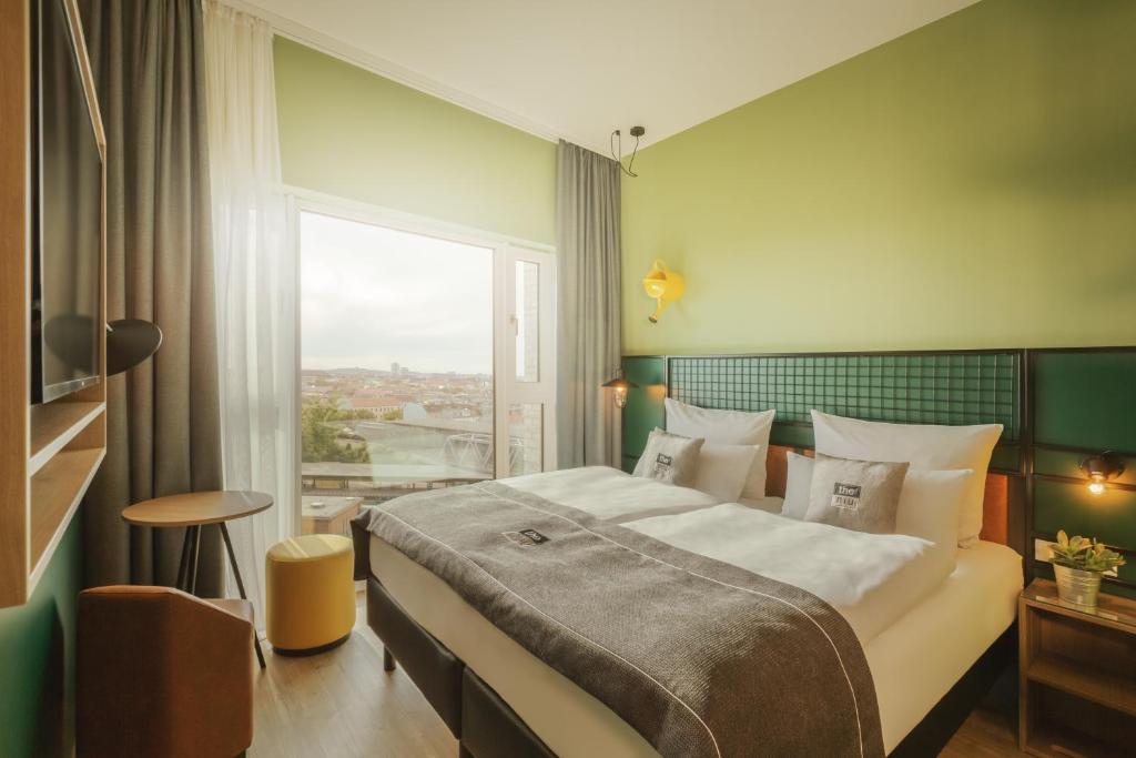 a bedroom with a large bed and a large window at the niu Dwarf in Berlin