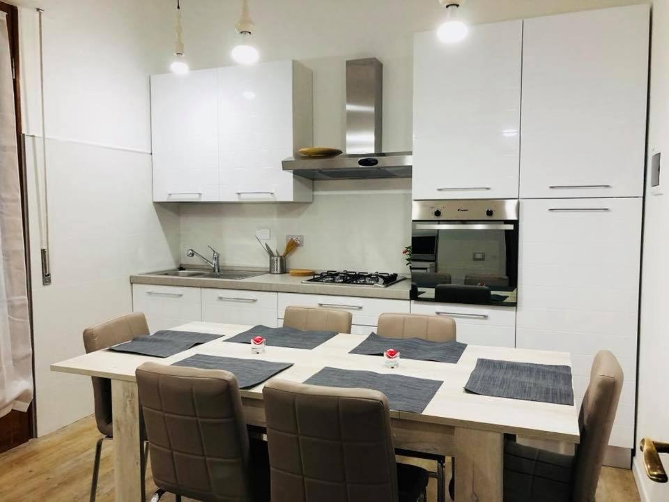 una cucina con tavolo, sedie e armadietti bianchi di Appartamento Daniela a Calenzano