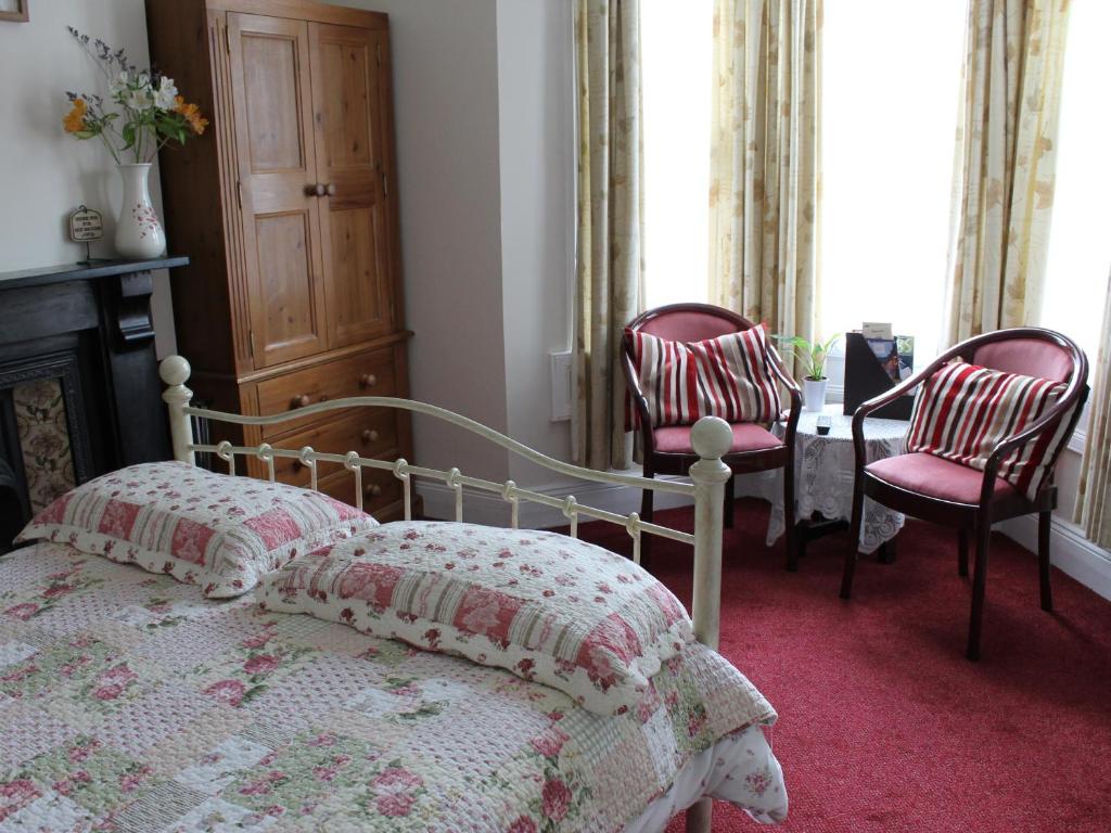 a bedroom with a bed and two chairs at White Guest House in Bath