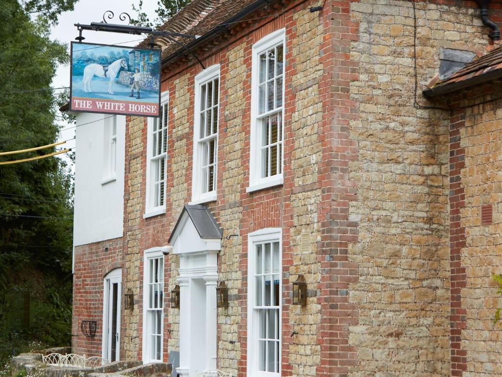 un edificio de ladrillo con un cartel en el costado en The White Horse Inn, en Pulborough