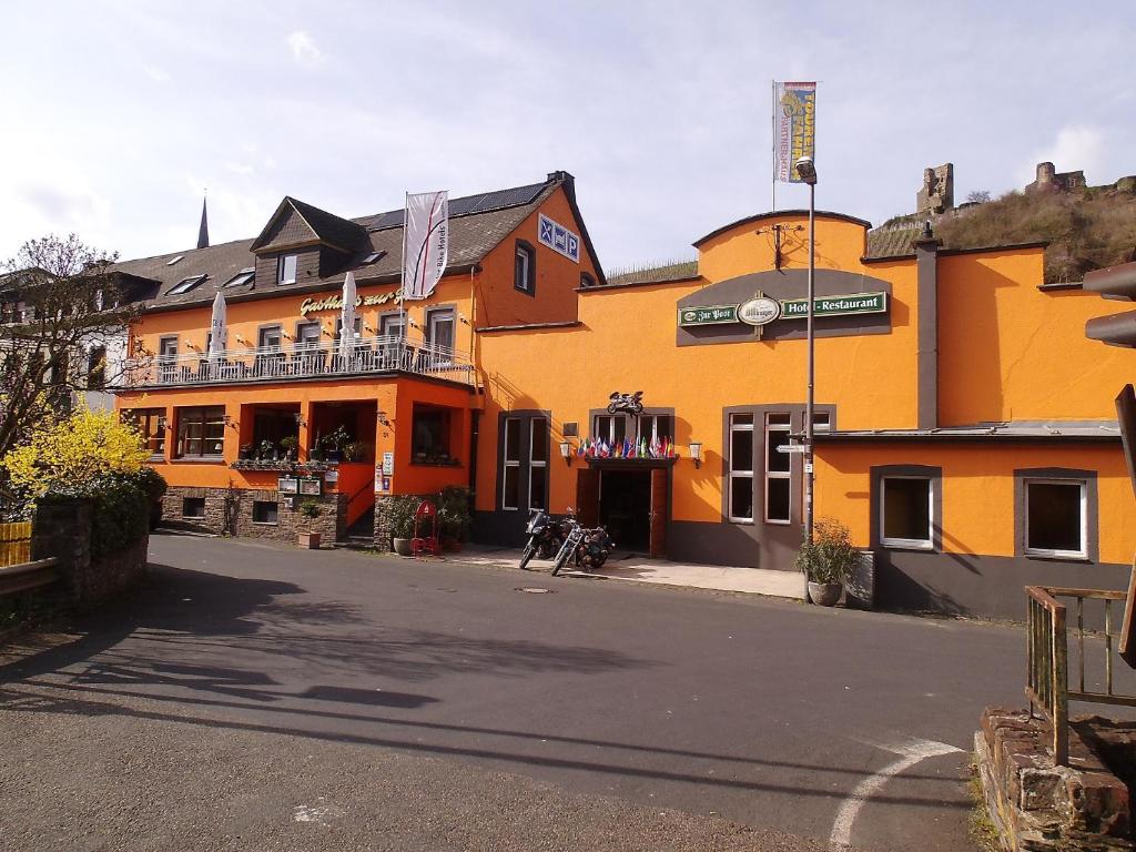 a yellow building with a balcony on a street at Hotel Zur Post in Klotten