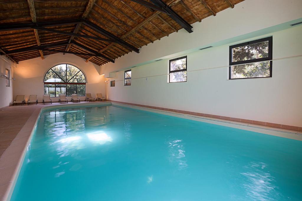 a large swimming pool with blue water in a building at Fattoria Pieve a Salti in Buonconvento