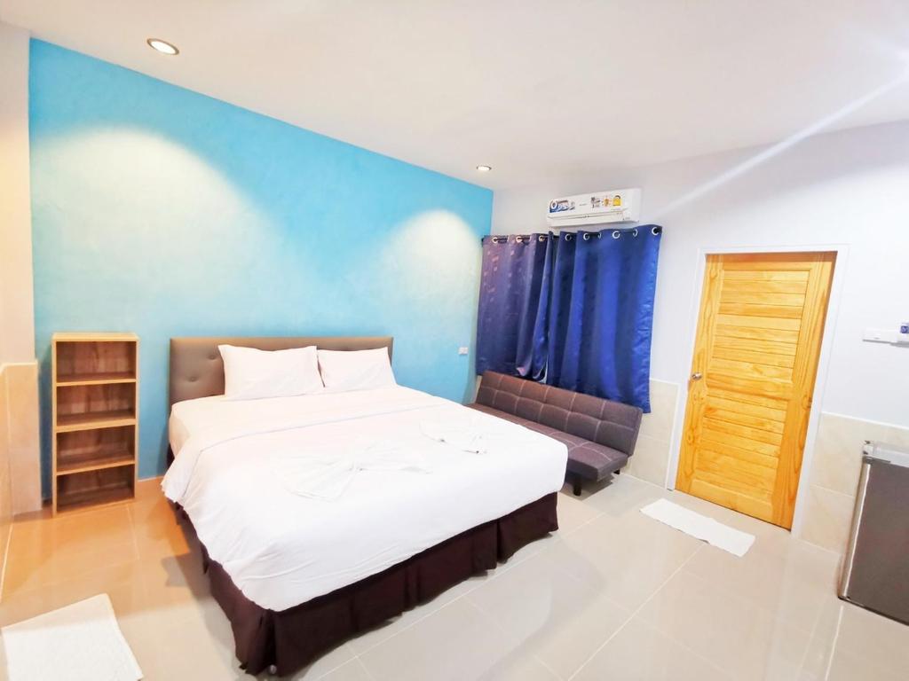 um quarto com uma cama grande e uma parede azul em ลิตเติ้ล ฮิลล์ สัตหีบ รีสอร์ท ( Little Hill Sattahip Resort ) em Sattahip