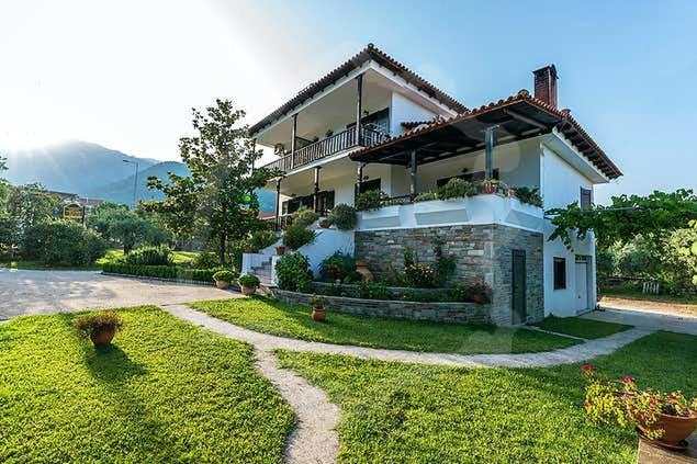 a large house with a lawn in front of it at Pantelidis Rooms in Skala Potamias