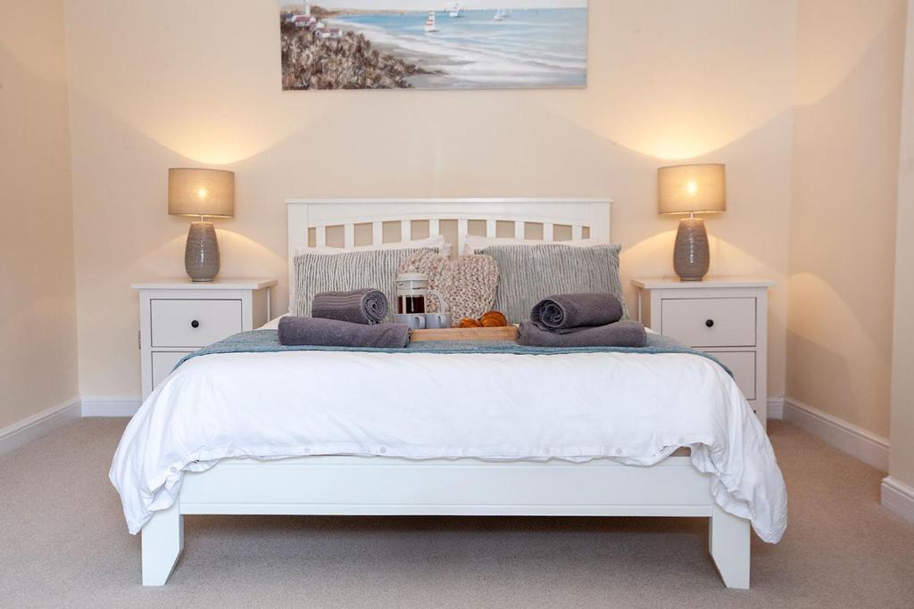 a bedroom with a white bed with two lamps at Clarence Cottage in Whitby